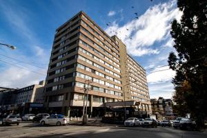 un edificio alto en una calle de la ciudad con coches aparcados en Departamentos Patagonia en San Carlos de Bariloche