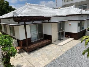 een wit huis met een veranda met een dak bij Condominium WAFU TEI Okinawa city in Okinawa City