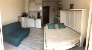 a bedroom with a bed and a couch and a kitchen at Studio rénové balcon ensoleillé et calme in La Londe-les-Maures