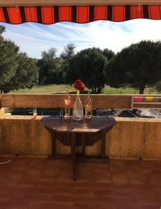 a table with two bottles and a vase with a flower on it at Studio rénové balcon ensoleillé et calme in La Londe-les-Maures