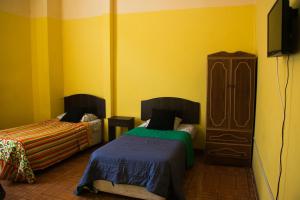 a yellow room with two beds and a dresser at Hostal Tricontinental in Valparaíso