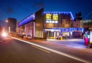 eine Stadtstraße in der Nacht mit einem Gebäude mit Lichtern in der Unterkunft OUGE Motel - Fengshan in Kaohsiung