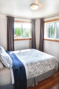 ein Schlafzimmer mit einem Bett und zwei Fenstern in der Unterkunft Willow Grove B&B Inn in Horsefly