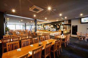 Mornington Hotel في مورنينغتون: غرفة طعام مع طاولات وكراسي خشبية