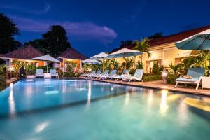 a swimming pool at night with chairs and umbrellas at Bali Nusa Cottage in Nusa Lembongan +36 photos
