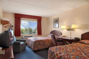 a hotel room with two beds and a desk and a television at Super 8 by Wyndham Manchester Airport in Manchester