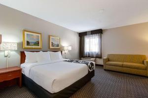 a hotel room with a large bed and a couch at La Quinta Inn by Wyndham Ft. Lauderdale Tamarac East in Fort Lauderdale