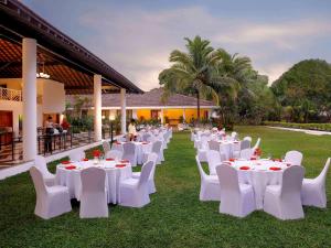 een groep witte tafels en stoelen in een tuin bij Novotel Goa Dona Sylvia Resort in Cavelossim