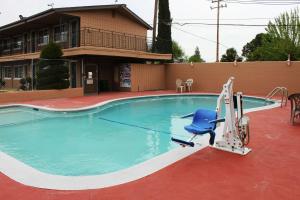 a swimming pool with a blue chair in front of a house at Rodeway Inn Near University-Gateway to Yosemite in Merced