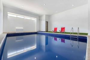a swimming pool with two red chairs in a room at Premier Inn Tuxtla in Tuxtla Gutiérrez