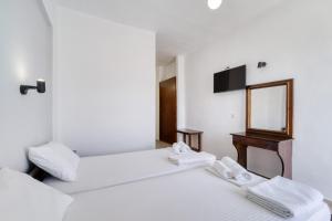 2 weiße Betten in einem Zimmer mit Spiegel in der Unterkunft Creta Star Apartments in Agia Galini