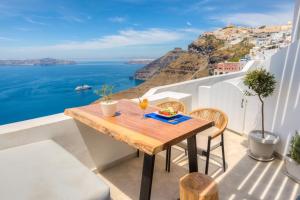 a table on a balcony with a view of the ocean at Iriana Suites in Fira