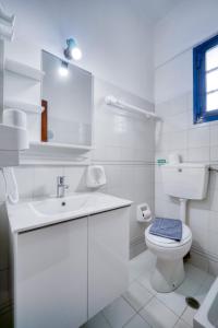 a white bathroom with a toilet and a sink at Creta Star Apartments in Agia Galini