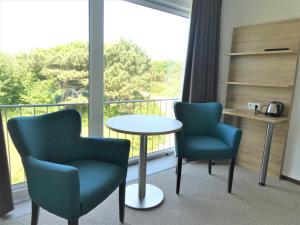 um quarto com 2 cadeiras, uma mesa e uma varanda em Strandhotel de Horn em Callantsoog