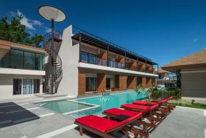 a swimming pool with lounge chairs and a house at Cher​mantra​ Aonang​ Resort & Pool​ Suite in Ao Nang Beach