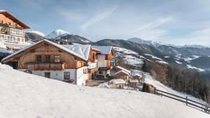 a house on a snowy hill with mountains in the background at Appartement Birkenhof in Maranza