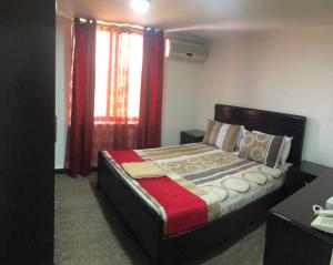 a bedroom with a bed and a window with red curtains at Masaya Al Deyar Apartments in Amman