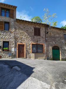 a stone house with two doors and a driveway at Casetta degli Etruschi ALLOGGIO TURISTICO in Allumiere