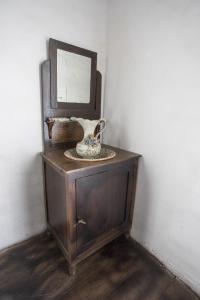 un armario de madera con espejo y un jarrón. en A Fonte das Bodas, en Samos