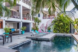 a swimming pool in the middle of a building with palm trees at Hôtel Villa Les Orchidées in Ambatoloaka