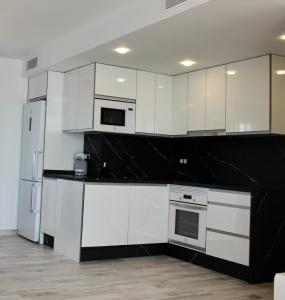 - une cuisine avec des appareils électroménagers blancs et des comptoirs noirs dans l'établissement Apartamento con vistas al mar, à Torrevieja