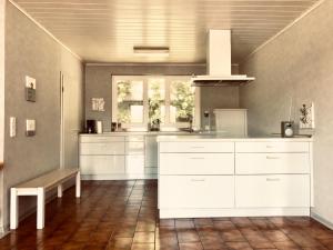 a large kitchen with white cabinets and a window at Talmühle Hirtscheid in Hirtscheid