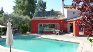 a swimming pool in front of a red house at Le mas de la diligence in Mirabeau