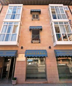 un edificio alto de ladrillo con ventanas y toldos azules en Hostal Cuéntame Evolución Auto Check in, en Burgos