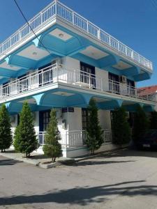 un bâtiment bleu et blanc avec des arbres devant lui dans l'établissement Nitsas studio's, à Kremasti