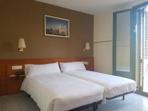 1 dormitorio con 1 cama grande con sábanas blancas en El Jardi, en Barcelona
