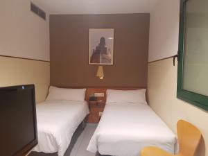 a room with two beds and a flat screen tv at El Jardi in Barcelona