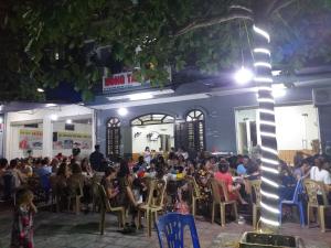 eine Menschenmenge, die vor einem Gebäude auf Stühlen sitzt in der Unterkunft Khách Sạn Hồng Tấn in Thương Xà (2)