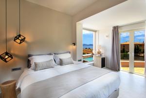 a bedroom with a large white bed and a large window at 180 South Seaside Hotel in Thermisía