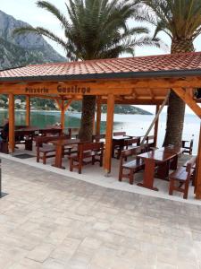 a wooden gazebo with picnic tables and palm trees at Apartments Anita in Gradac