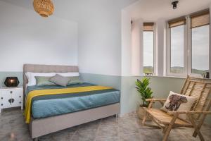 a bedroom with a bed and a chair and windows at Villa Alessandra in Markópoulon