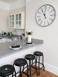 una cocina con 4 taburetes y un reloj en la pared en Heart of Southsea,near common and sea., en Portsmouth