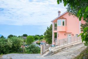 uma casa cor-de-rosa na berma de uma estrada em Villa Alessandra em Markópoulon