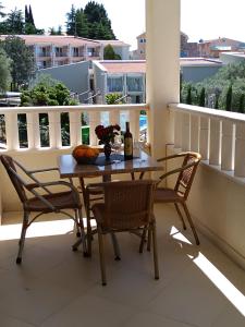 a table with two chairs and a bottle of wine on a balcony at Vila V Lux Apartments in Petrovac na Moru