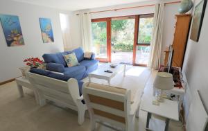 a living room with a blue couch and a table at Menlo At C in Plettenberg Bay