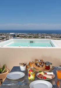 a table with plates of food and a swimming pool at Nalas Suites in Emporio Santorini