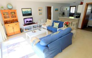 uma sala de estar com um sofá azul e uma mesa em Menlo At C em Plettenberg Bay