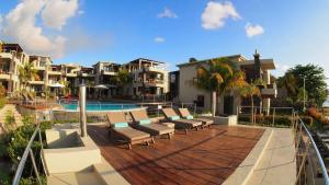 a deck with chairs and a pool in a resort at Beach Apartment - Trou aux Biches - Ground Floor in Mont Choisy