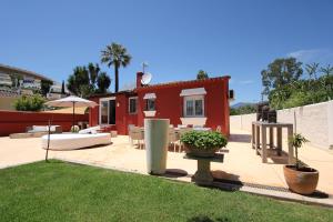 マルベーリャにあるvilla in puerto banusの赤い家屋(テーブルと椅子付)のある裏庭