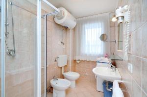 La salle de bains est pourvue de toilettes, d'un lavabo et d'une douche. dans l'établissement Residence Corallo, à Caorle