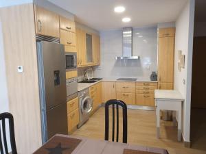 a kitchen with wooden cabinets and a stainless steel refrigerator at LA GATERA 1D BAJO ARAGON - MATARRAÑA in Fabara