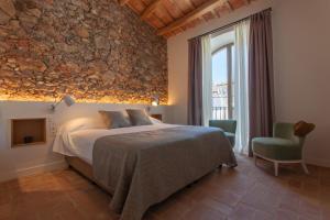 um quarto com uma cama e uma parede de pedra em Can Liret em Palafrugell