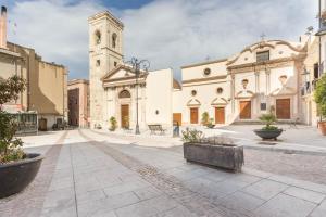una calle con una iglesia y una torre del reloj en Via San Giacomo 10, en Cagliari