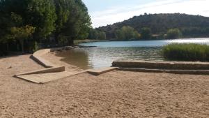 a beach with a body of water and trees at Camping-Hotel Los Molinos in Ruidera