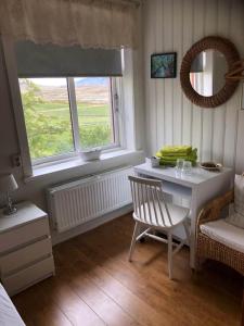 een kamer met een tafel, een stoel en een raam bij Ferðaþjónustan Geitaskarði in Geitaskard