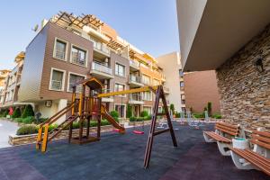 a playground in a courtyard with a building at Aпартаменти Хоризонт in Sozopol